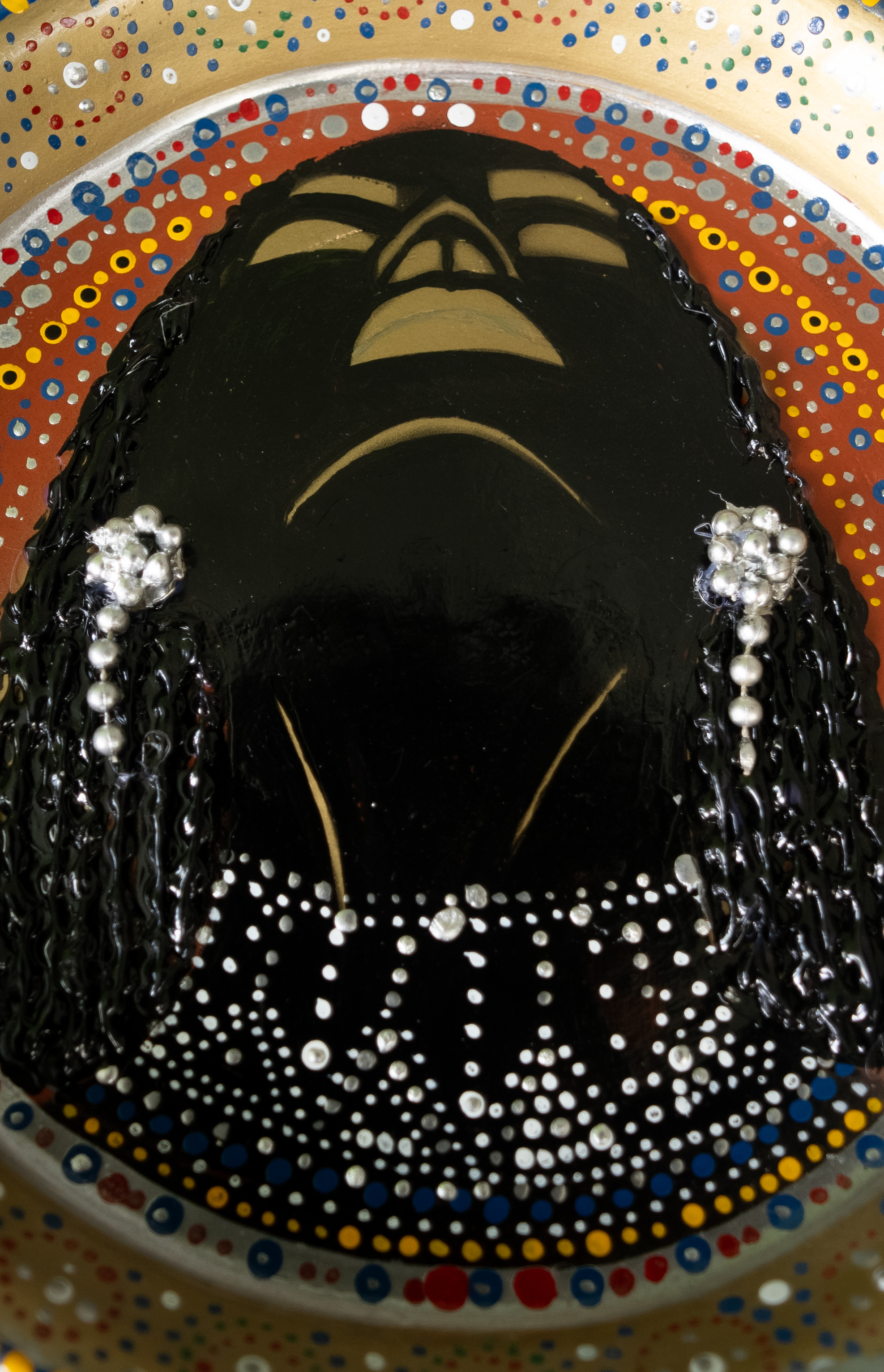 Circular relief portrait with braided hair, jewellery and concentric dotted bands