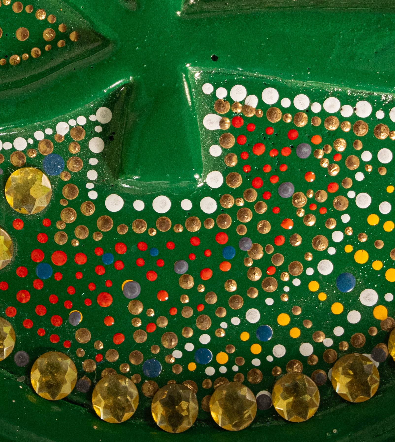 Dotted green surface with raised geometric forms and gold accents